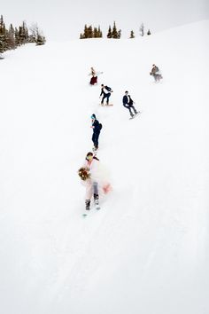 a group of people riding down the side of a snow covered slope on skis