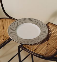 a white plate sitting on top of a wooden chair next to a brown rattan seat