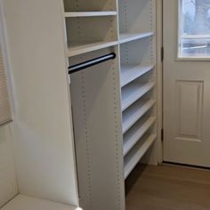 an empty walk - in closet with white shelves and drawers, next to a door