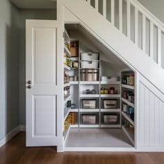 an under the stairs storage area in a house with white walls and wooden floors,