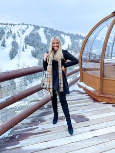 a woman standing on a wooden deck next to a ski lift