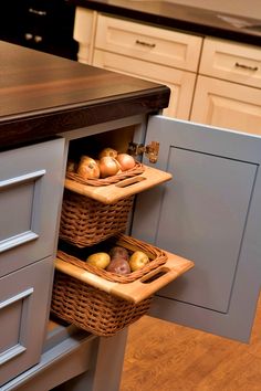 two wicker baskets hold apples and onions in the corner of a kitchen cabinet door