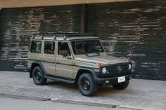 a mercedes g - class is parked in front of a building