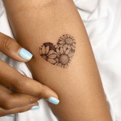 a woman's arm with flowers on it and a heart tattoo in the middle