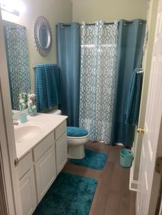 a bathroom with blue rugs and shower curtain