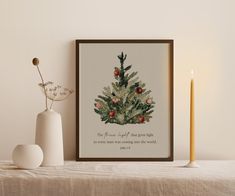 a christmas tree with ornaments on it next to a lit candle and a framed print