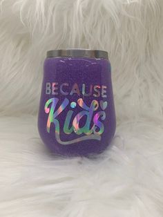 a purple tumbler with the words because kids on it sitting on a fluffy white surface