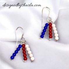 red, white and blue beads are hanging from silver earwires on a white cloth