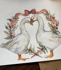 two white ducks with bows on their heads and flowers in front of them, making a heart shape