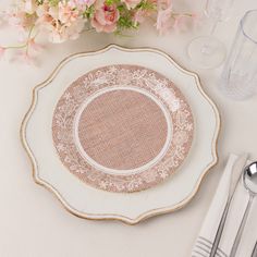 a white and gold plate sitting on top of a table next to silver utensils