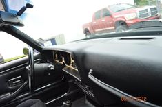 the interior of a car with its door open and dashboard lights turned on in front of other cars