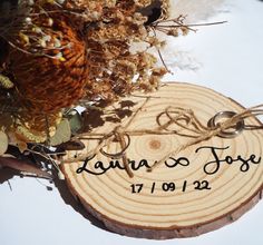 a wooden slice with the names of two people on it and some dried flowers in front