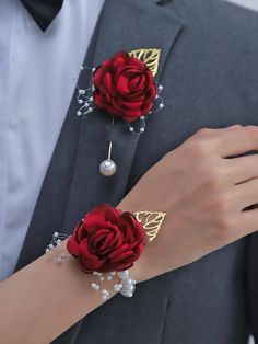 a man in a tuxedo with two red roses on his lapel and pearl bracelets