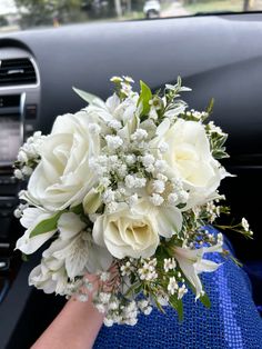 a bouquet of white flowers sitting on top of a blue cloth next to a car dashboard