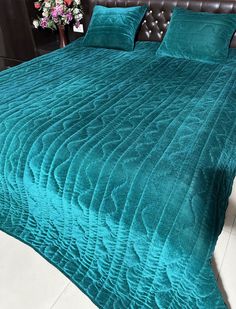 the bed is made up with teal colored bedspreads