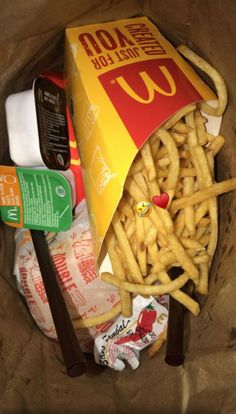 french fries, ketchup, mayonnaise and other condiments in a paper bag