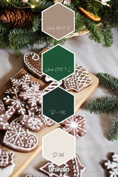 some cookies are sitting on a table next to pine cones and fir branches with the colors green, brown, and white