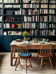 a table with two chairs in front of a bookshelf