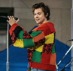 a man in a colorful sweater holding a microphone