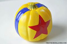 a yellow and blue pumpkin with a red star painted on it's side sitting on a white surface