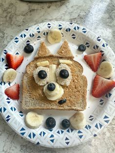 a plate topped with bread and fruit on top of a table next to a bowl of strawberries