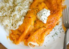 a white plate topped with pasta covered in cheese and sauce next to rice on top of a wooden table