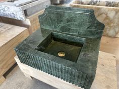 a green marble sink sitting on top of a wooden table next to other pieces of wood