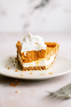 a slice of pumpkin pie on a plate with whipped cream and cinnamon crumbs