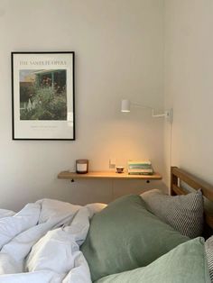 an unmade bed with green and white sheets in a bedroom next to a shelf