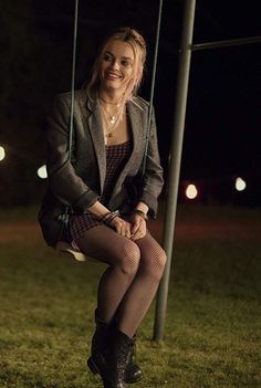 a woman is sitting on a swing at night with her legs crossed and wearing tights