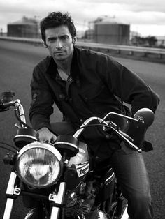 a man riding on the back of a motorcycle down a street next to a highway