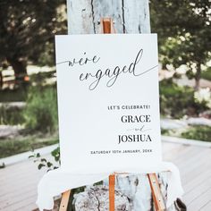 an easel with a sign on it that says we're engaged and the date is written in cursive