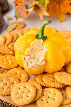 an orange sitting on top of crackers next to some pumpkins and autumn leaves