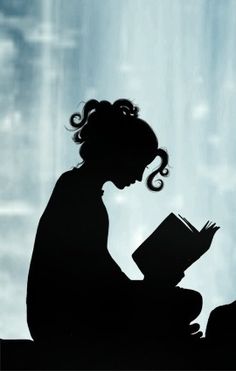 the silhouette of a woman reading a book