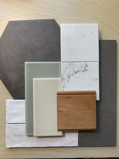 several different types of tiles and wood on a wooden surface with white, gray, brown, and black colors