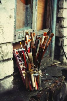 there are many paint brushes in a cup on the window sill next to an open door