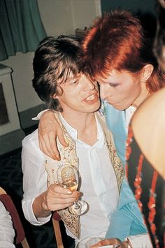 two women hugging each other while holding wine glasses