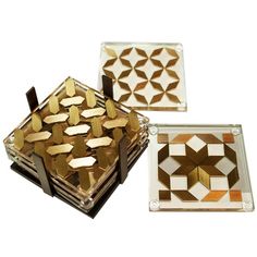 two glass coasters with gold and white designs on them, one in the shape of a square