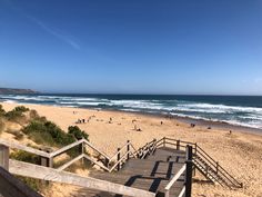 people are walking up and down the stairs to the beach on a clear sunny day