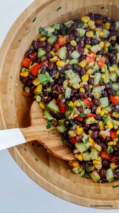 a wooden bowl filled with black beans and veggies