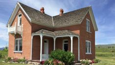 a red brick house with white trim on the front porch and two dormers is shown