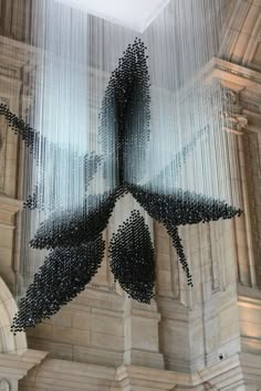 a sculpture made out of black and white beads on the ceiling in a large building