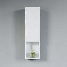 a white wall mounted cabinet with a green vase in the corner on it's left side