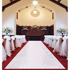 the aisle is lined with white tulle and bows, along with flowers in vases