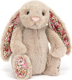 a stuffed rabbit with flowers on it's ears and nose, sitting in front of a white background