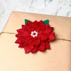 a gift wrapped in brown paper with a red flower on it