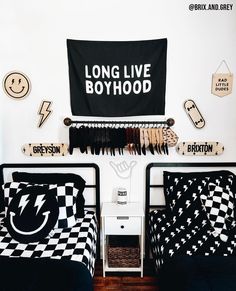 two twin beds with black and white bedding in a boys'bedroom, one has a long live boyhood banner on the wall