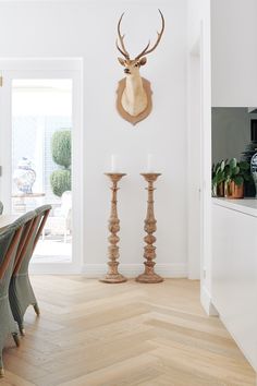 a deer head mounted on the wall above a dining room table with two candlesticks