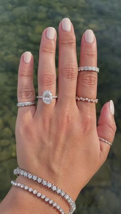 a woman's hand with three different rings on her left and two diamond bracelets on her right