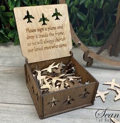 an open wooden box with some cut out airplanes in it and the words please sign a plane and drop it inside the frame, so we will always christ our loved ones who came